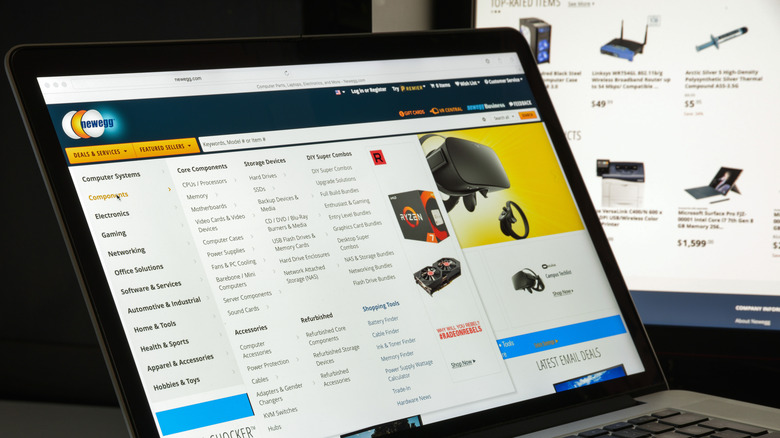 Веб-сайт Newegg на ноутбуке перед монитором другого компьютера