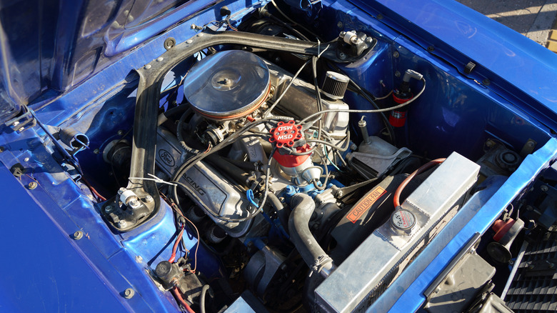 Крупный план настроенного двигателя Ford 302 в моторном отсеке синего маслкара.
