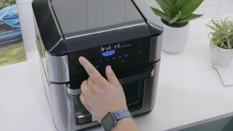 человек нажимает Instant Pot Vortex Plus
