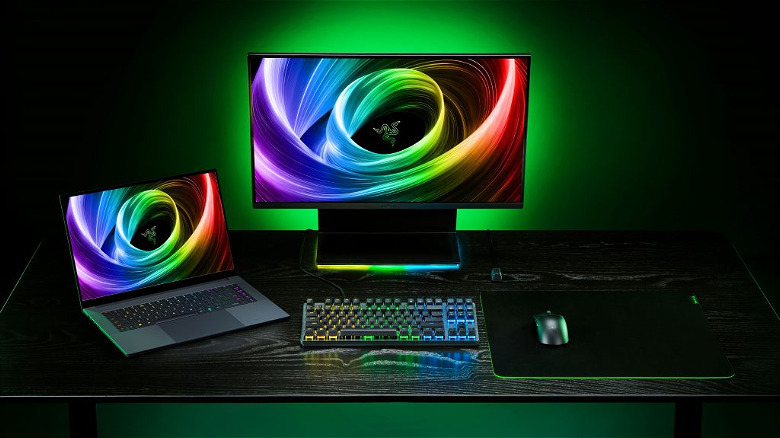 Razer Blade 16 на столе, подключенный к внешнему монитору, мыши и клавиатуре с зеленой подсветкой.