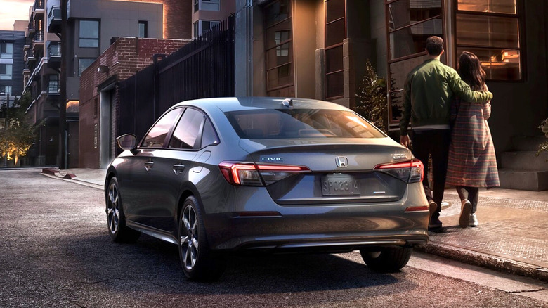 Пара, стоящая рядом с Honda Civic