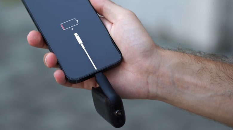 Рука держит мертвый смартфон с подключенным к USB-порту Rolling Square Tau 2