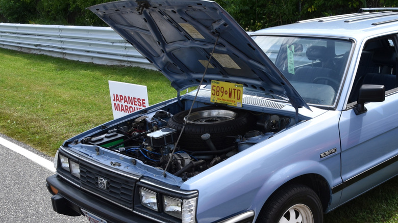 Subaru GL 1984 года с открытым капотом, виднеется двигатель и запасное колесо.