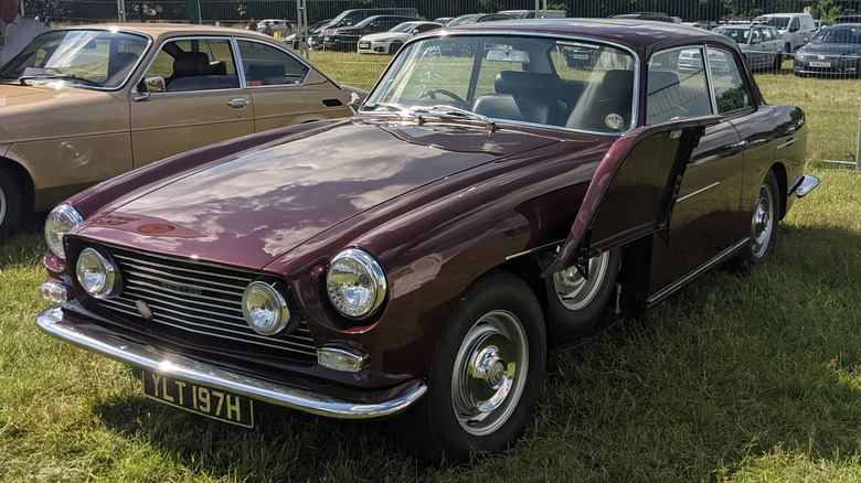 Maroon Bristol 410 припаркован на траве с открытой крышкой запасного колеса, вид в 3/4 спереди слева