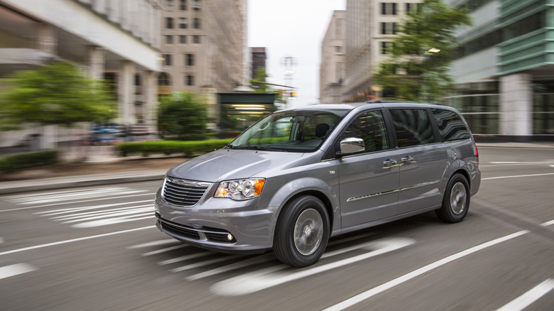 Минивэн Chrysler Town & Country 2014 года движется по городской дороге, вид спереди слева в 3/4