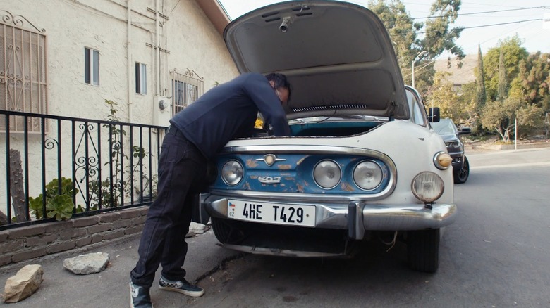 Tatra 603 с человеком, осматривающим открытый люк доступа к запасному колесу, вид спереди