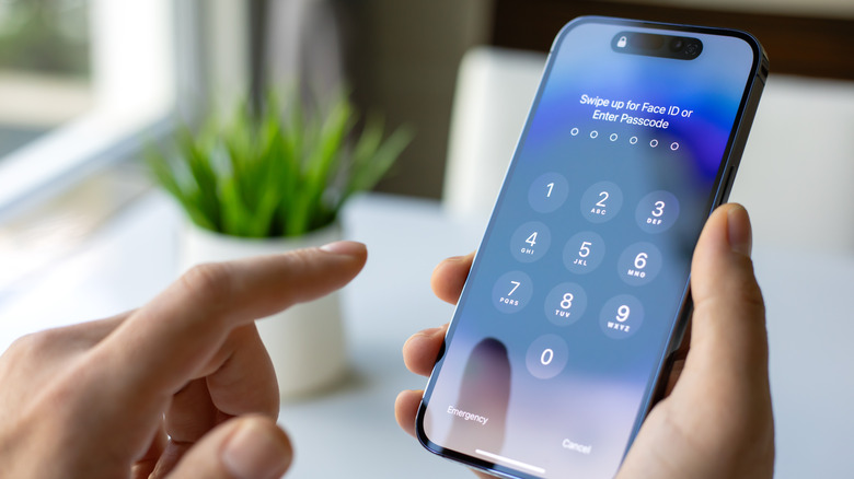 Человек, держащий iPhone 15 с экраном блокировки