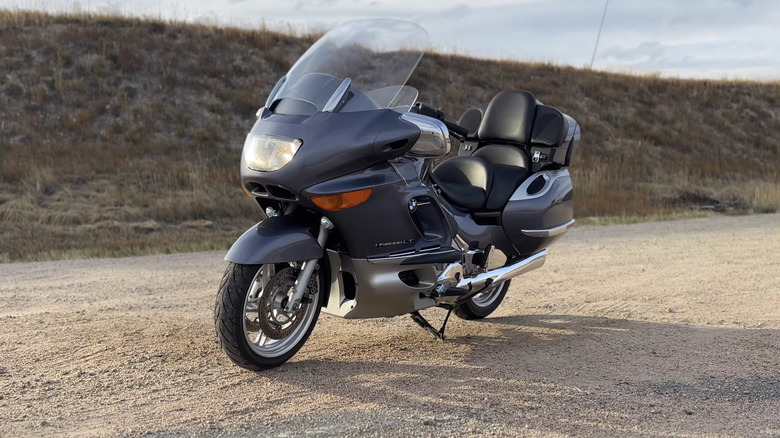 Серебристый туристический круизер BMW K1200 LT, припаркованный на грязи лицом справа налево.