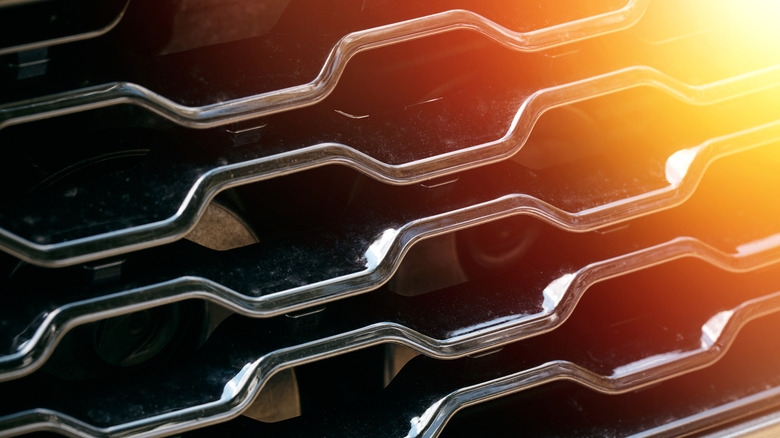 Изображение солнечного света, сияющего на передней решетке автомобиля