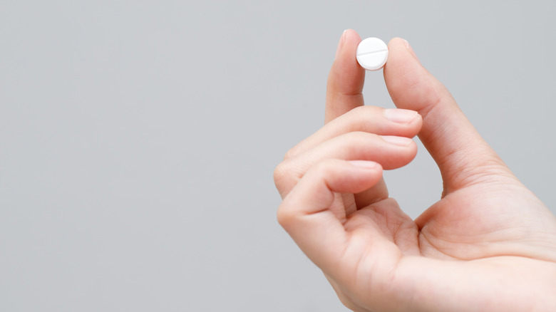 Рука человека держит таблетку