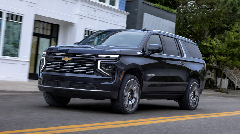 Темно-синий Chevrolet Suburban едет по городской дороге.