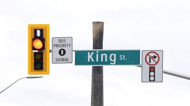 Светофор с сигналом приоритета автобуса на фоне белого неба