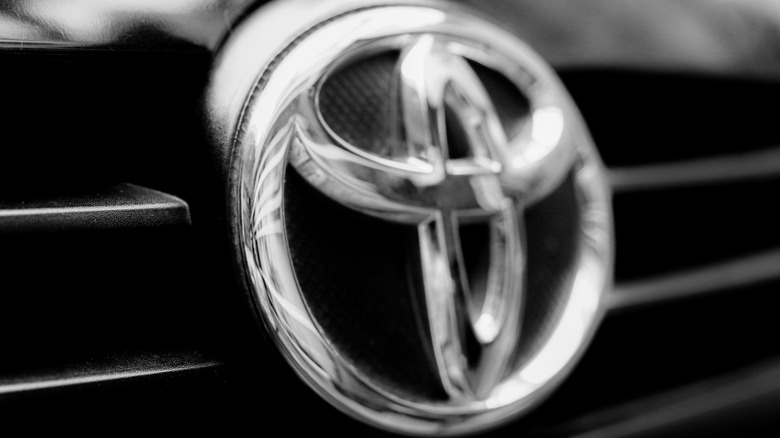 Крупный план неглубокого изображения логотипа Toyota на решетке автомобиля.