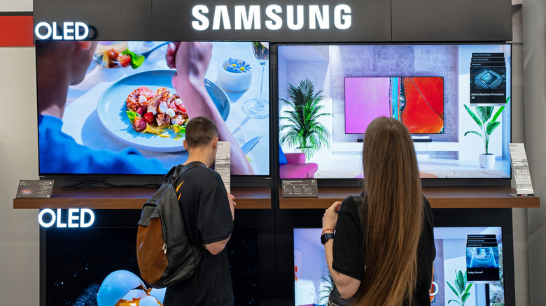 Покупатели просматривают OLED-телевизоры Samsung в магазине электроники