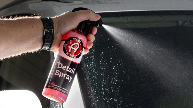 Рука распыляет спрей Adam's Polishes Detail Spray на автомобиль.