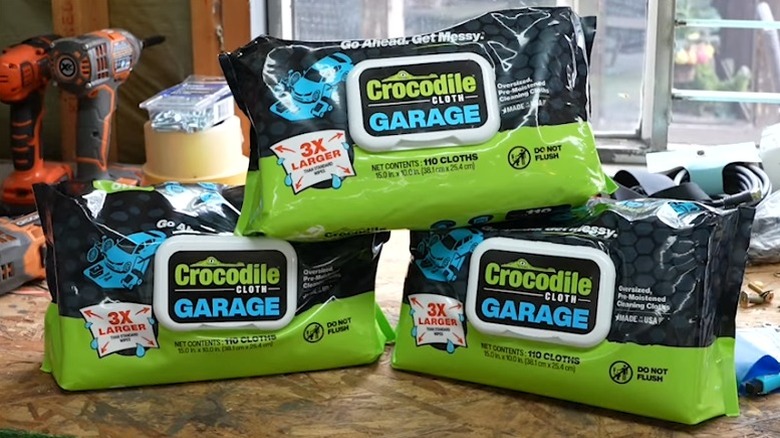 Три упаковки гаражных салфеток из крокодиловой ткани, сложенные на столе в мастерской