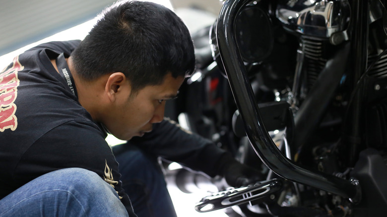 Техник работает на мотоцикле Harley-Davidson.