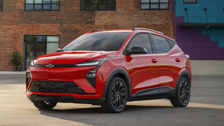 Вид спереди на красный Chevrolet Bolt 2027 года выпуска, припаркованный перед кирпичным зданием