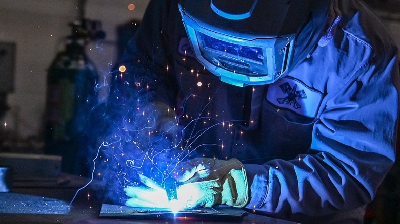 Механик сваривает кусок металла.