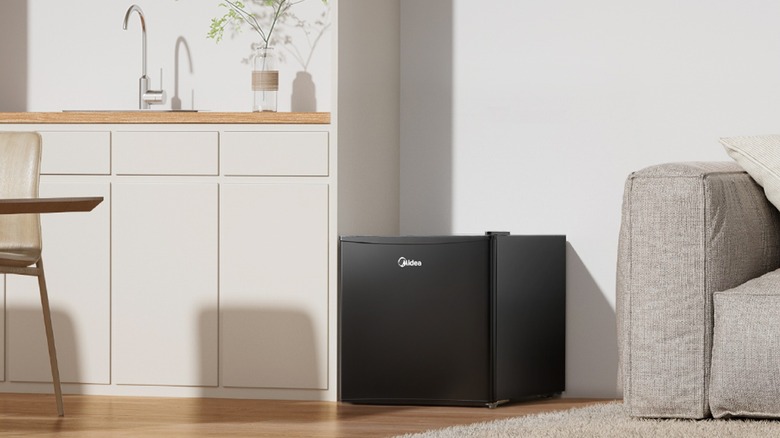 Холодильник Midea в гостиной, у стены.