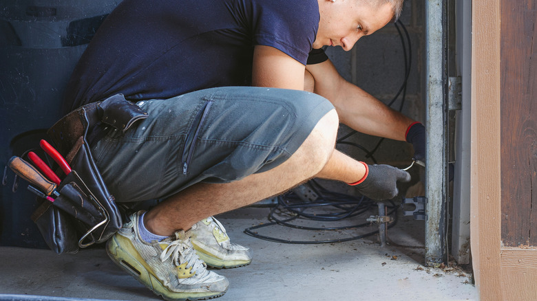 Мужчина ремонтирует датчики гаражных ворот