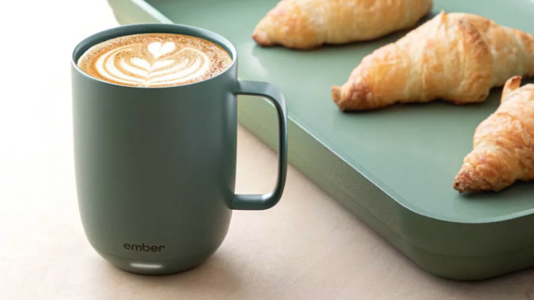 Угольная кружка рядом с подносом с выпечкой