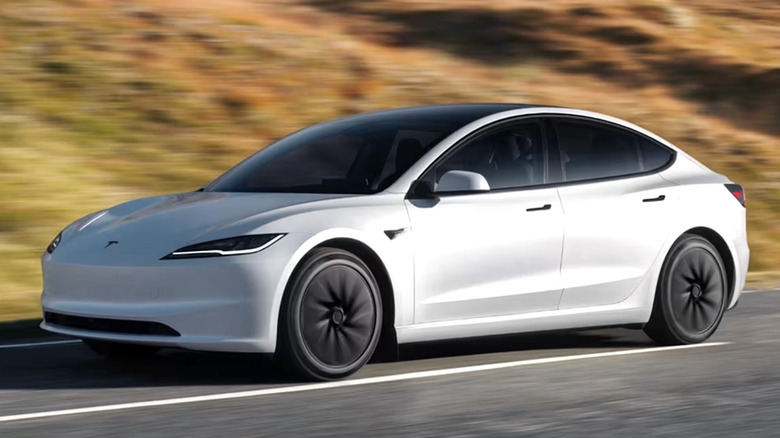 Белая Tesla Model 3 едет по сельской дороге