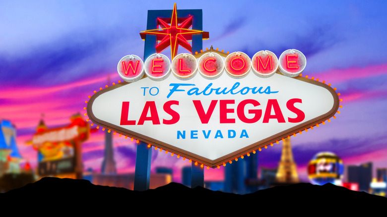 Вывеска Лас-Вегаса светится в сумерках, а за ней горит полоса.