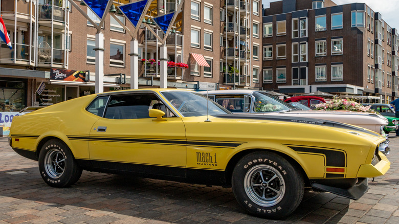 Классический желтый Mustang Mach 1, припаркованный на витрине, оснащенный шинами Goodyear.