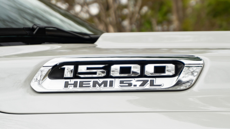 Крупный план значка RAM 1500 Hemi 5.7L на белом крыле.