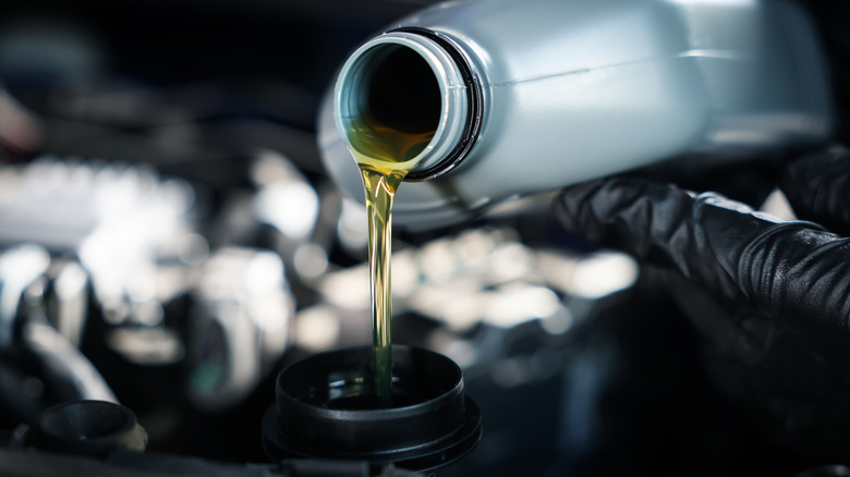 Человек заливает моторное масло в машину