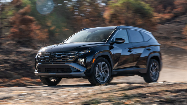 Черный Hyundai Tucson Hybrid 2026 года едет по лесной тропе.