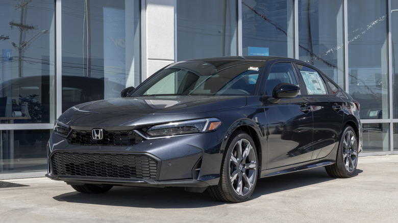 Вид спереди 3/4 серого седана Honda Civic Hybrid, припаркованного у дилера.