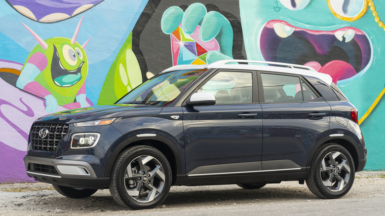 Вид спереди на 3/4 Hyundai Venue, припаркованного на грязи перед фреской