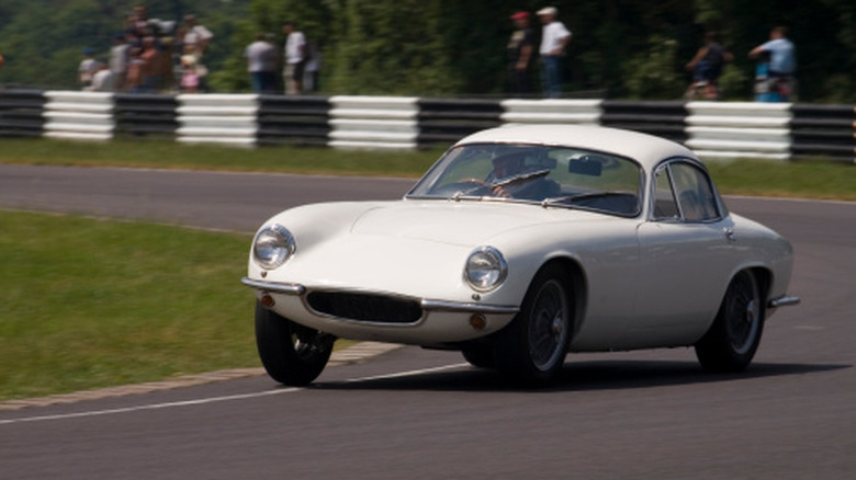 Белый классический автомобиль поворачивает на гоночной трассе.