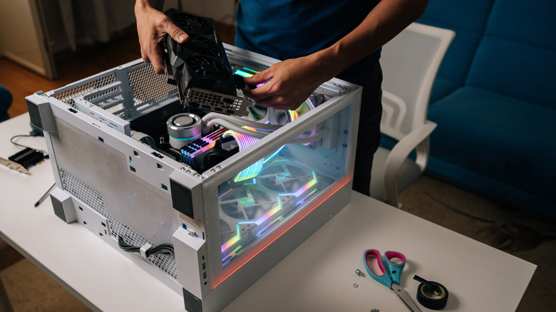 Техник устанавливает видеокарту в настольный ПК