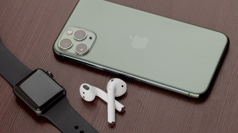 Apple Watch и пара AirPods рядом с Apple iPhone на деревянной поверхности