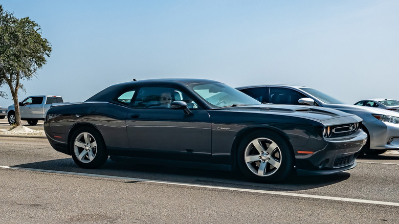 Вид сбоку серого Dodge Challenger 2015 года выпуска за рулем.