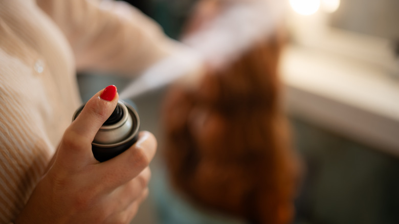 Человек распыляет аэрозольный баллончик в воздух.