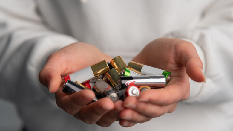 Человек держит в руках много батареек.