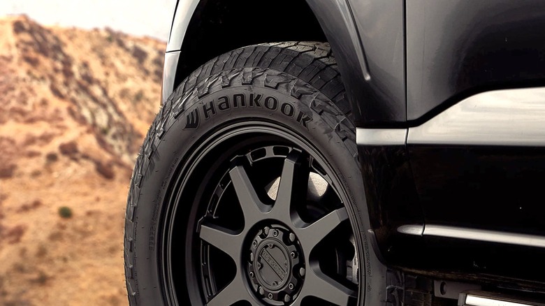 Крупный план надписи Hankook на комплекте вездеходных шин, на заднем плане пустыня.