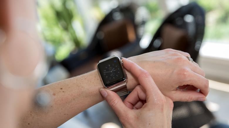 Человек, использующий Apple Watch на фоне автомобиля