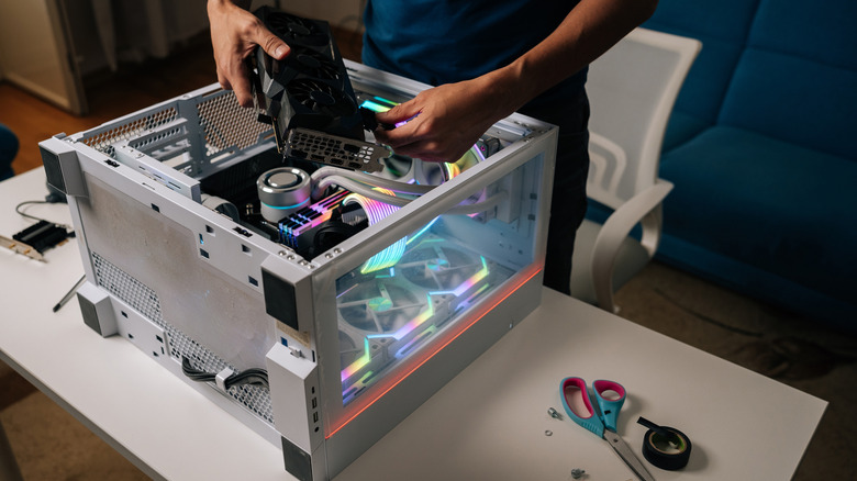 компьютерный техник устанавливает новую видеокарту в изготовленный на заказ компьютер