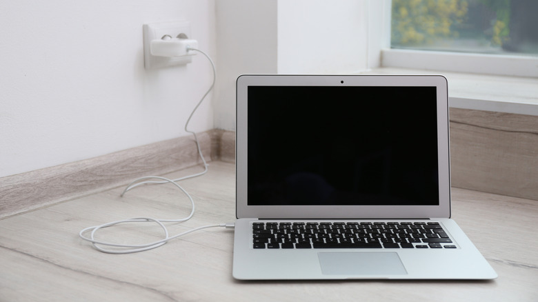 Современный ноутбук стоит на полу во время зарядки