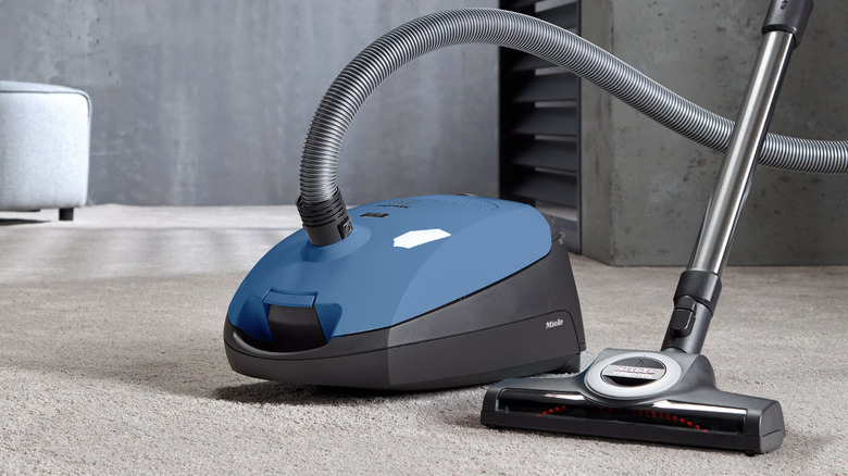 Miele Classic C1 Turbo Team PowerLine синего цвета на коричневом ковре.