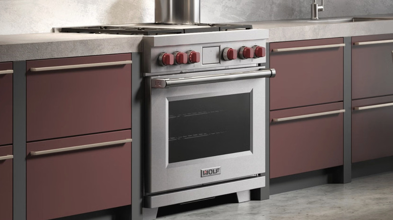 Серия Wolf с красными ручками, установленными в современных темно-красных шкафах со светлой столешницей и фартуком.