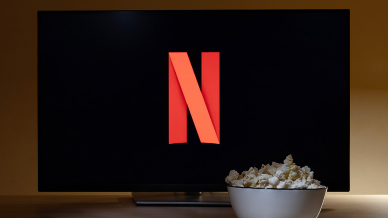 Телевизор с символом Netflix и белая миска попкорна перед ним.