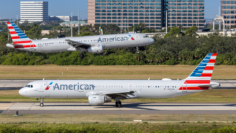 Самолет American Airlines рулит по взлетно-посадочной полосе, на заднем плане взлетает самолет American Airlines.