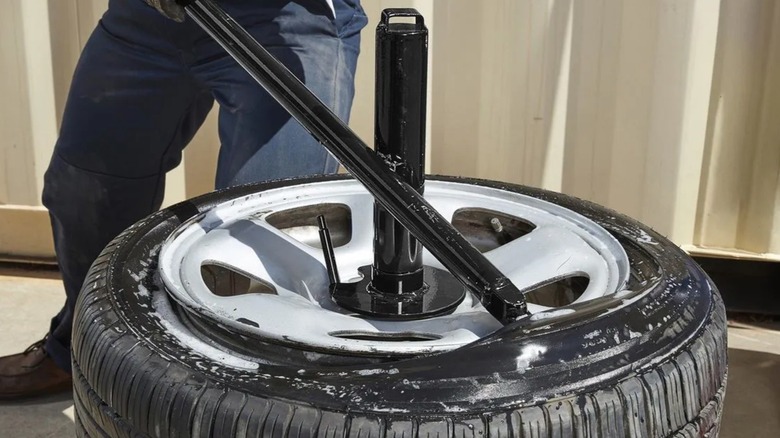 Человек, использующий шиномонтажный станок Harbour Freight для замены шины