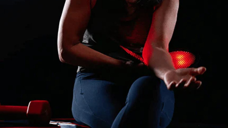 Женщина использует устройство красного света на предплечье